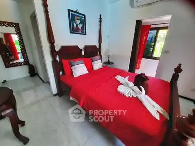 Charming bedroom with vibrant red bedding and elegant wooden furniture, perfect for a cozy retreat.