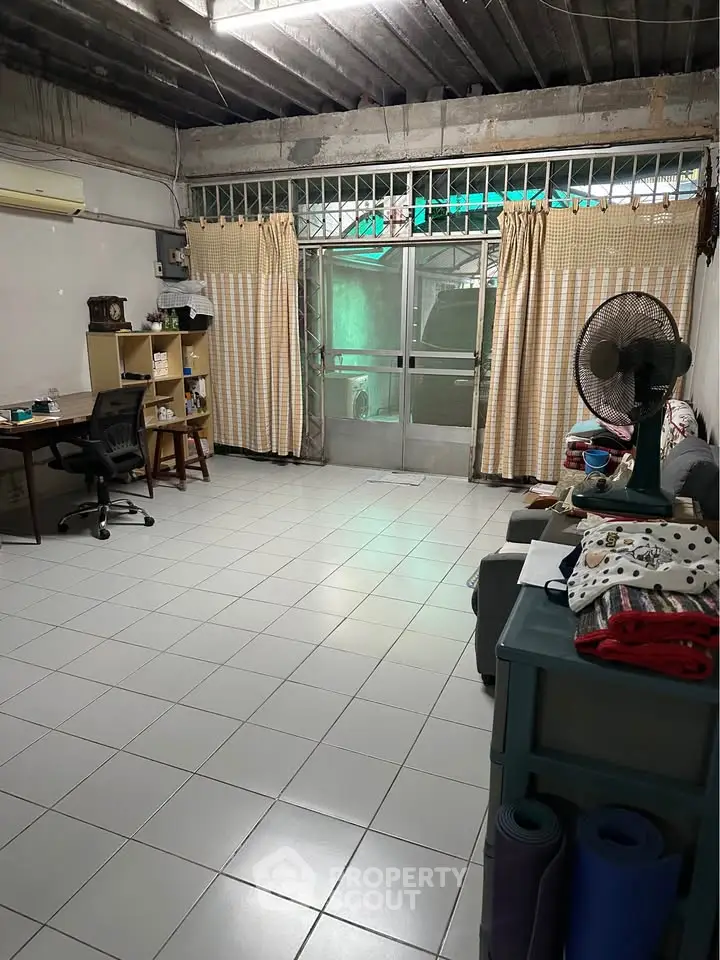 Spacious living room with tiled floor, desk, and fan, ideal for versatile living arrangements.