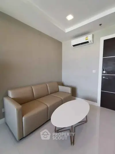 Modern living room with sleek sofa and minimalist decor, featuring a wall-mounted air conditioner.