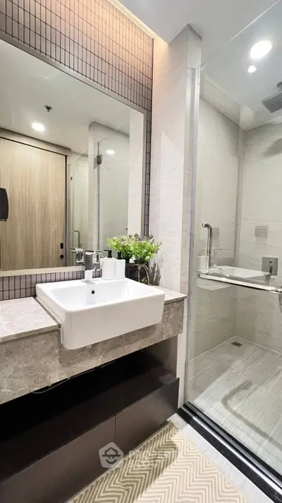 Modern bathroom with sleek design, featuring a spacious shower and elegant sink area.