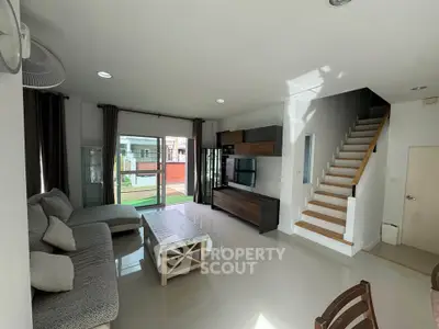 Spacious living room with modern decor and natural light, featuring a cozy sofa and sleek entertainment unit.