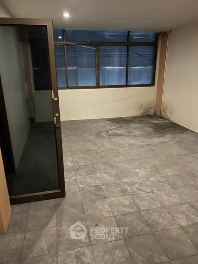 Spacious empty room with large windows and tiled flooring, ideal for customization.