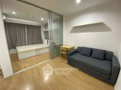 Modern studio apartment with glass partition, cozy sofa, and wooden flooring.