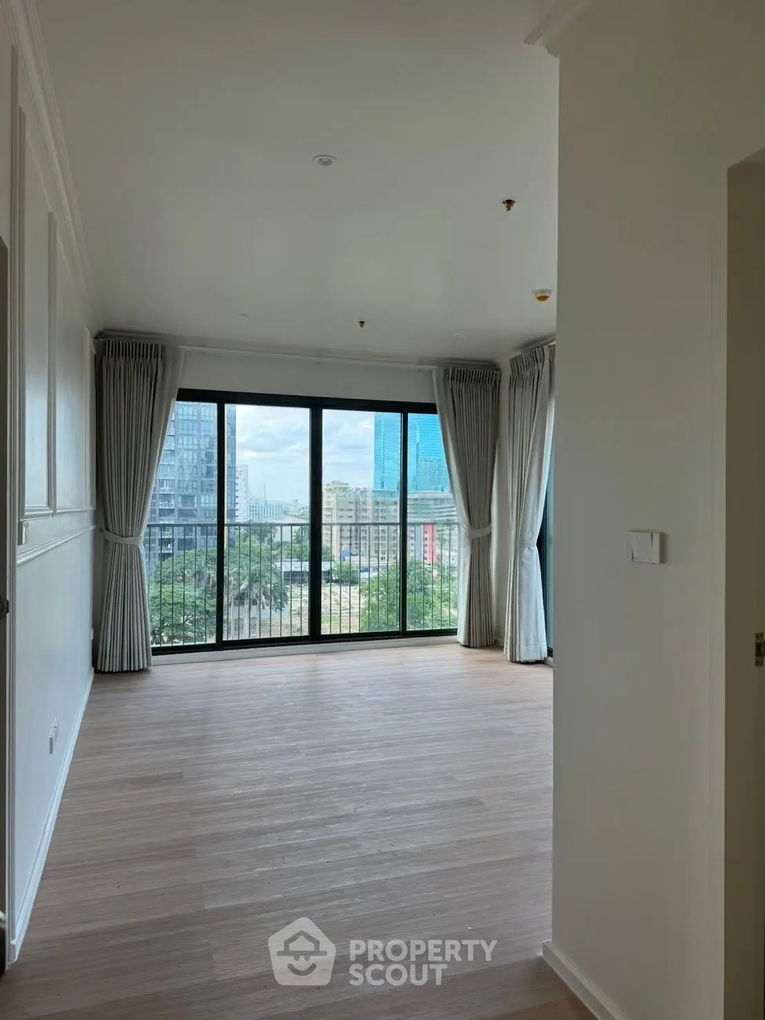 Spacious living room with large windows offering a stunning city view, perfect for modern urban living.