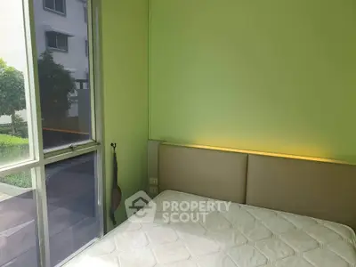 Cozy bedroom with green walls and large window offering natural light and garden view.