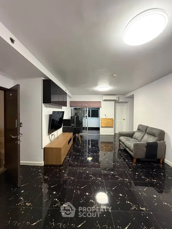 Spacious modern living room with sleek black marble flooring and stylish furniture.