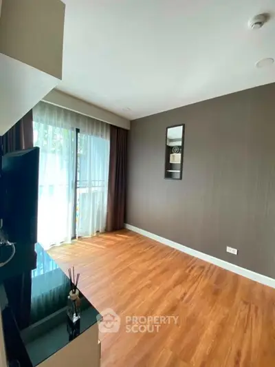 Spacious living room with wooden flooring and large window in modern apartment