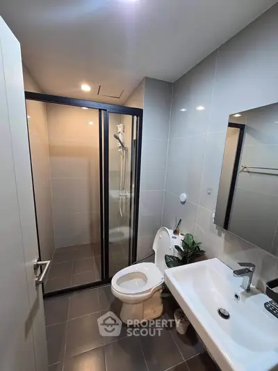 Modern bathroom with sleek design, featuring a glass shower enclosure and contemporary fixtures.