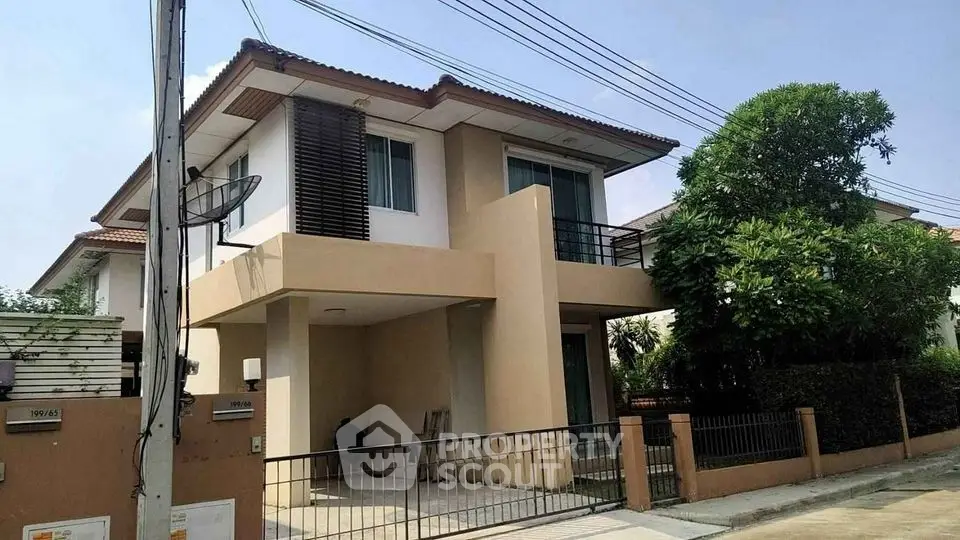 Modern two-story house with a spacious balcony and lush greenery, perfect for family living.