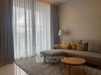 Elegant living room with modern sofa, floor-to-ceiling windows, and stylish decor.