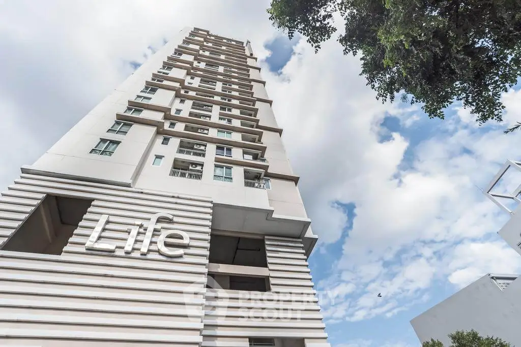Modern high-rise building with unique architectural design against a blue sky.
