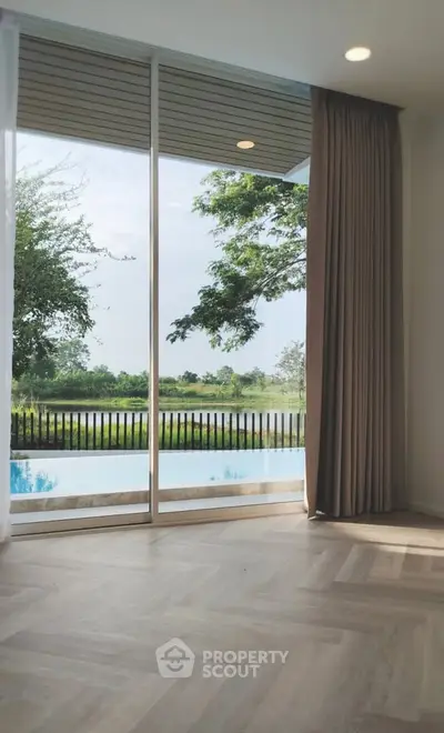 Luxurious living room with floor-to-ceiling windows offering stunning pool and garden views.
