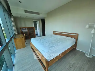 Spacious bedroom with large windows and wooden furniture in modern apartment