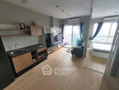 Modern open-plan living room with kitchen and bedroom, featuring large windows and stylish furnishings.