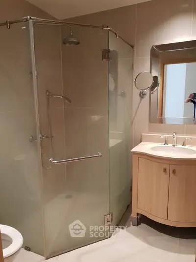 Modern bathroom with glass shower enclosure and wooden vanity in a stylish apartment.