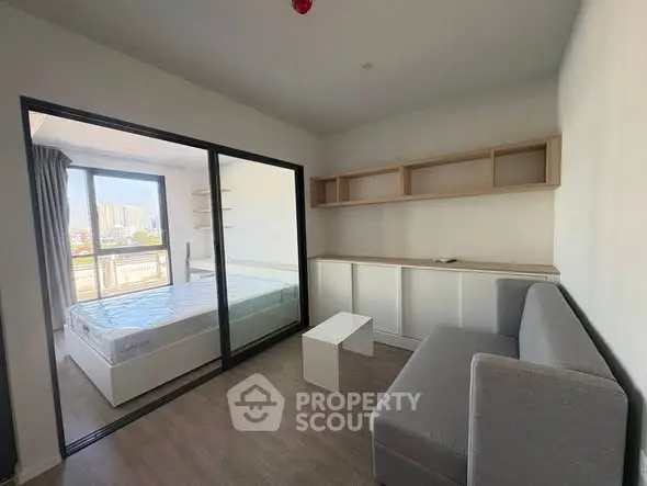 Modern apartment interior with sliding glass doors, cozy living area, and natural light-filled bedroom.