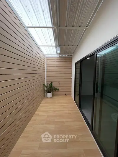 Modern enclosed balcony with wooden paneling and glass sliding doors