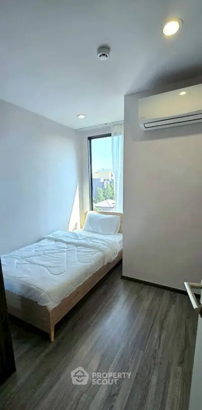 Modern bedroom with city view and air conditioning, featuring sleek flooring and minimalist design.