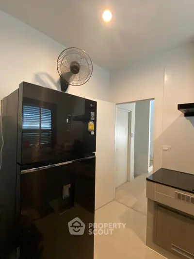 Modern kitchen with sleek black fridge and built-in appliances, perfect for contemporary living.