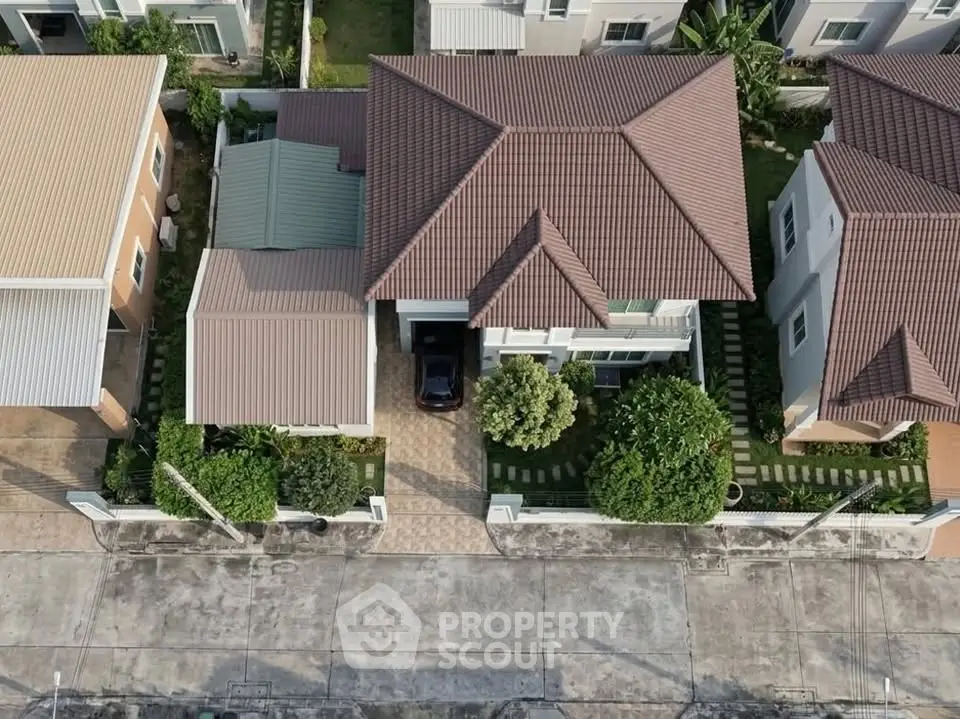 Aerial view of a modern suburban house with a tiled roof and landscaped garden.