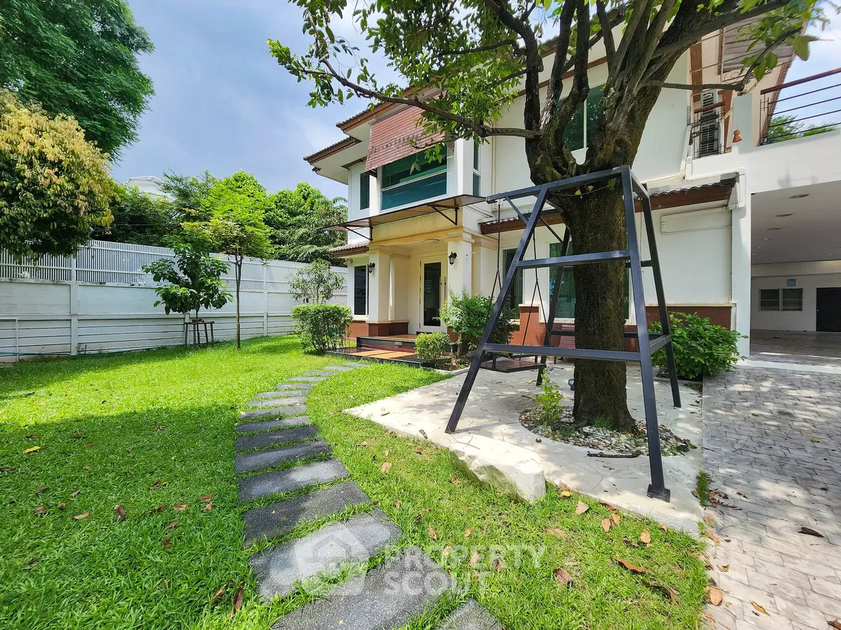 Charming two-story house with lush garden and swing in a serene neighborhood.