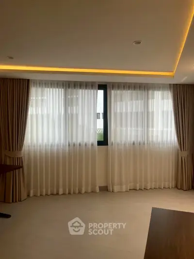 Spacious living room with elegant curtains and soft lighting, perfect for relaxation and entertainment.