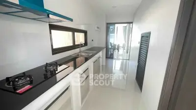 Sleek modern kitchen with gas stove and glossy white cabinetry in a contemporary apartment.