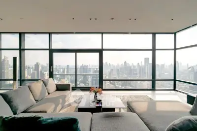 Luxurious living room with panoramic city skyline view, modern furniture, and floor-to-ceiling windows.