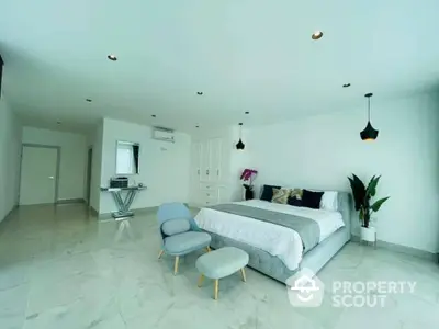 Spacious bedroom with modern design, king-sized bed, elegant lighting, and a cozy sitting area, featuring a sleek marble floor and white walls.