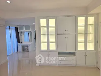 Spacious modern living room with built-in white cabinetry and elegant vanity area.