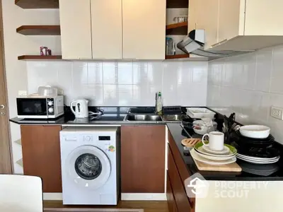 Modern kitchen with washing machine and sleek cabinetry in compact layout