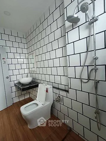 Modern bathroom with stylish white tiles and wooden flooring, featuring a sleek shower and contemporary fixtures.