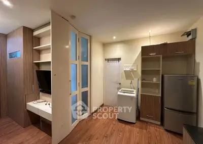Modern apartment interior with washing machine and fridge in open layout kitchen.