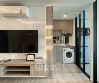 Modern living room with sleek kitchen and washing machine, featuring elegant wood finishes and ambient lighting.