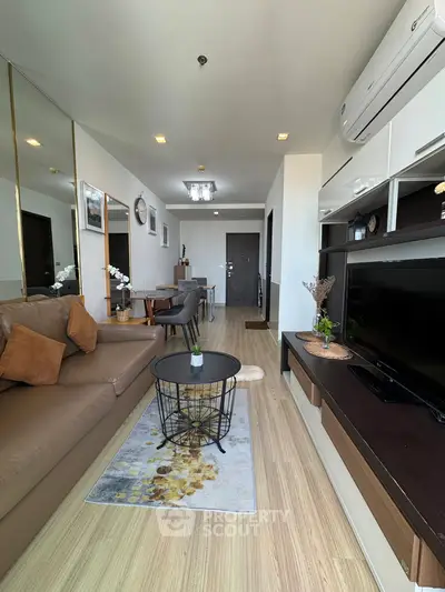 Modern living room with stylish decor and open layout, featuring a cozy sofa and sleek entertainment unit.