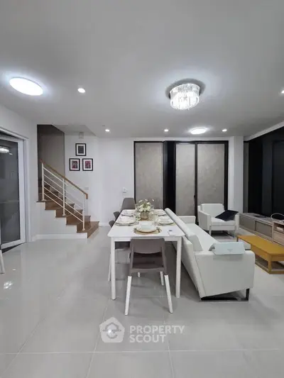 Modern open-plan living and dining area with elegant decor and staircase