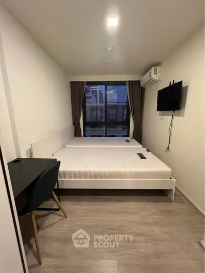 Modern bedroom with large window and wall-mounted TV in a stylish apartment.