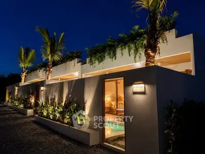 Luxurious modern villa with lush greenery and ambient lighting at night, featuring a private pool and palm trees.