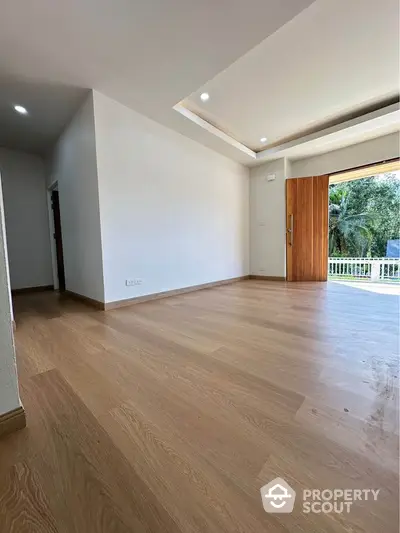 Spacious modern living room with wooden flooring and large balcony access.