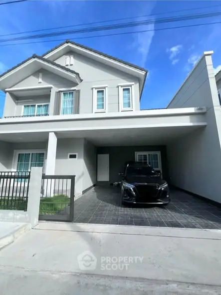 Modern two-story house with carport and sleek black car in driveway.