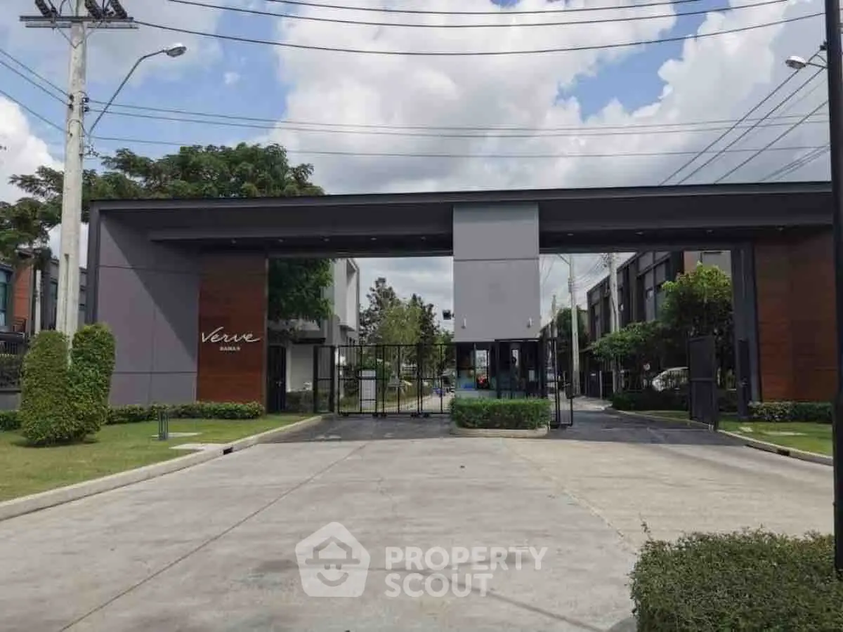 Modern gated community entrance with sleek design and lush greenery.