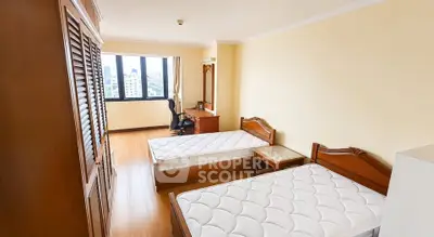 Spacious bedroom with twin beds and city view, ideal for comfortable living.