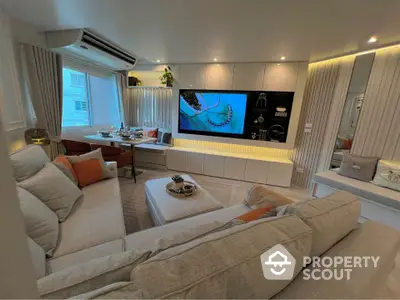 Modern living room with stylish decor and large TV, featuring cozy seating and elegant lighting.