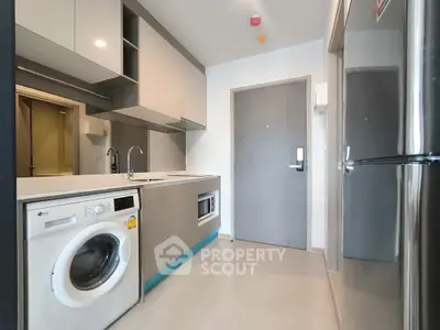 Modern kitchen with sleek appliances and washing machine in compact layout.