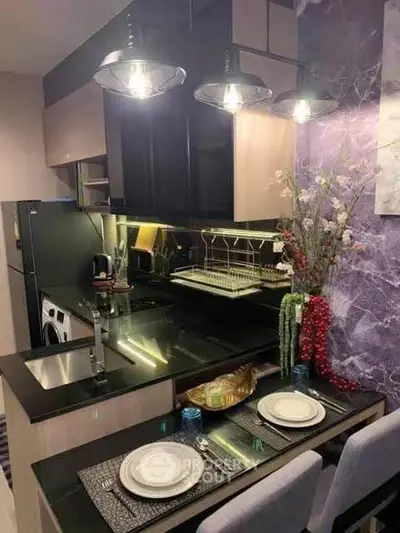 Modern kitchen with sleek black countertops, stylish lighting, and elegant dining setup in a cozy apartment.
