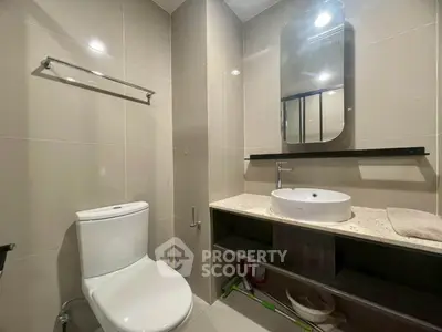 Modern bathroom with sleek fixtures and elegant design, featuring a stylish mirror and contemporary sink.