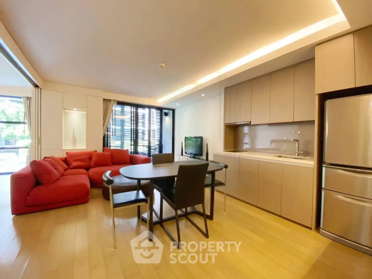 Modern open-layout living room with red sofa and sleek kitchen in a stylish apartment.