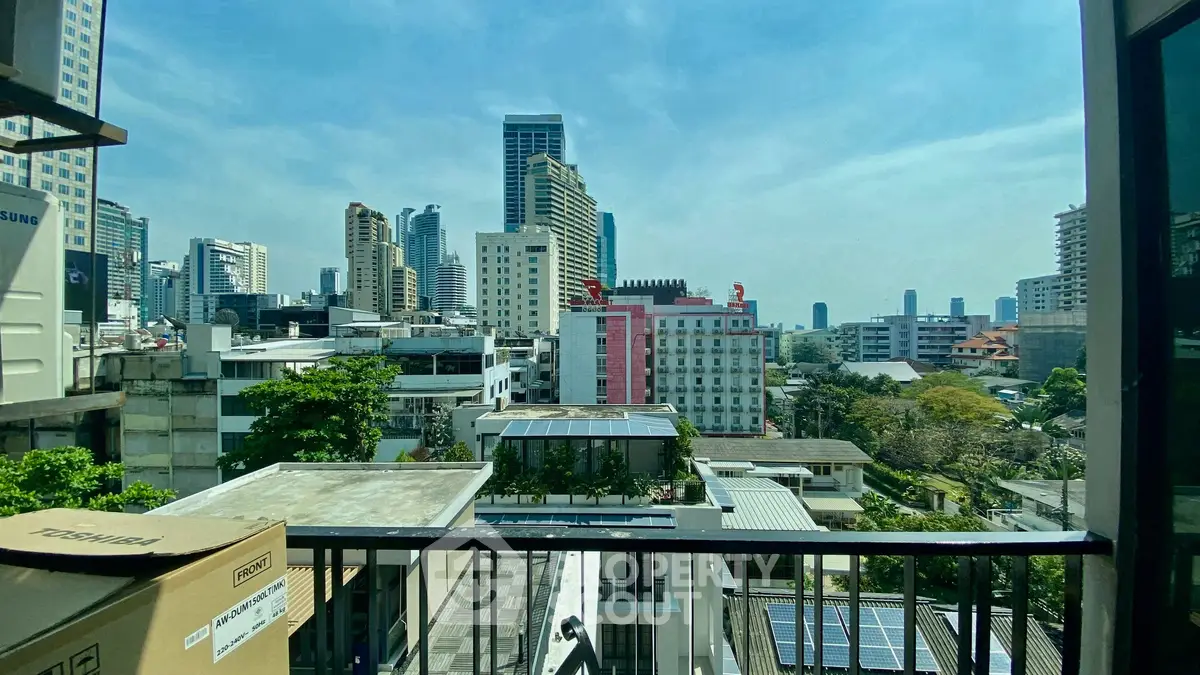 Stunning cityscape view from a high-rise balcony showcasing urban skyline and lush greenery.