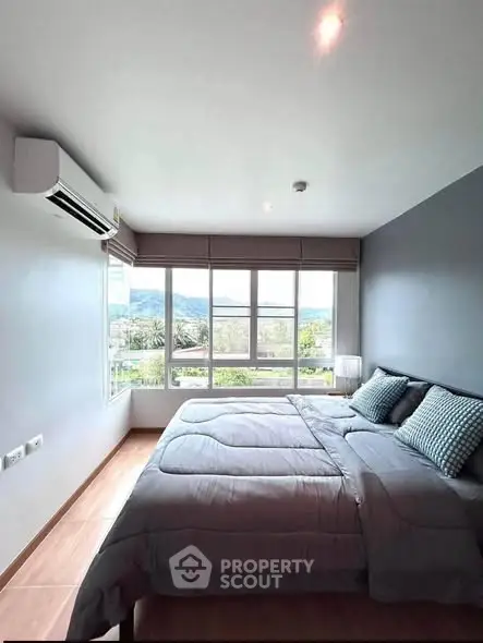 Spacious bedroom with large windows offering scenic views, modern decor, and air conditioning.