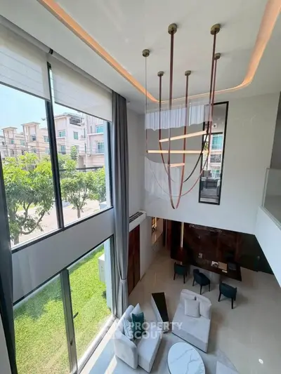 Luxurious modern living room with high ceilings and elegant chandelier, featuring large windows and stylish furniture.